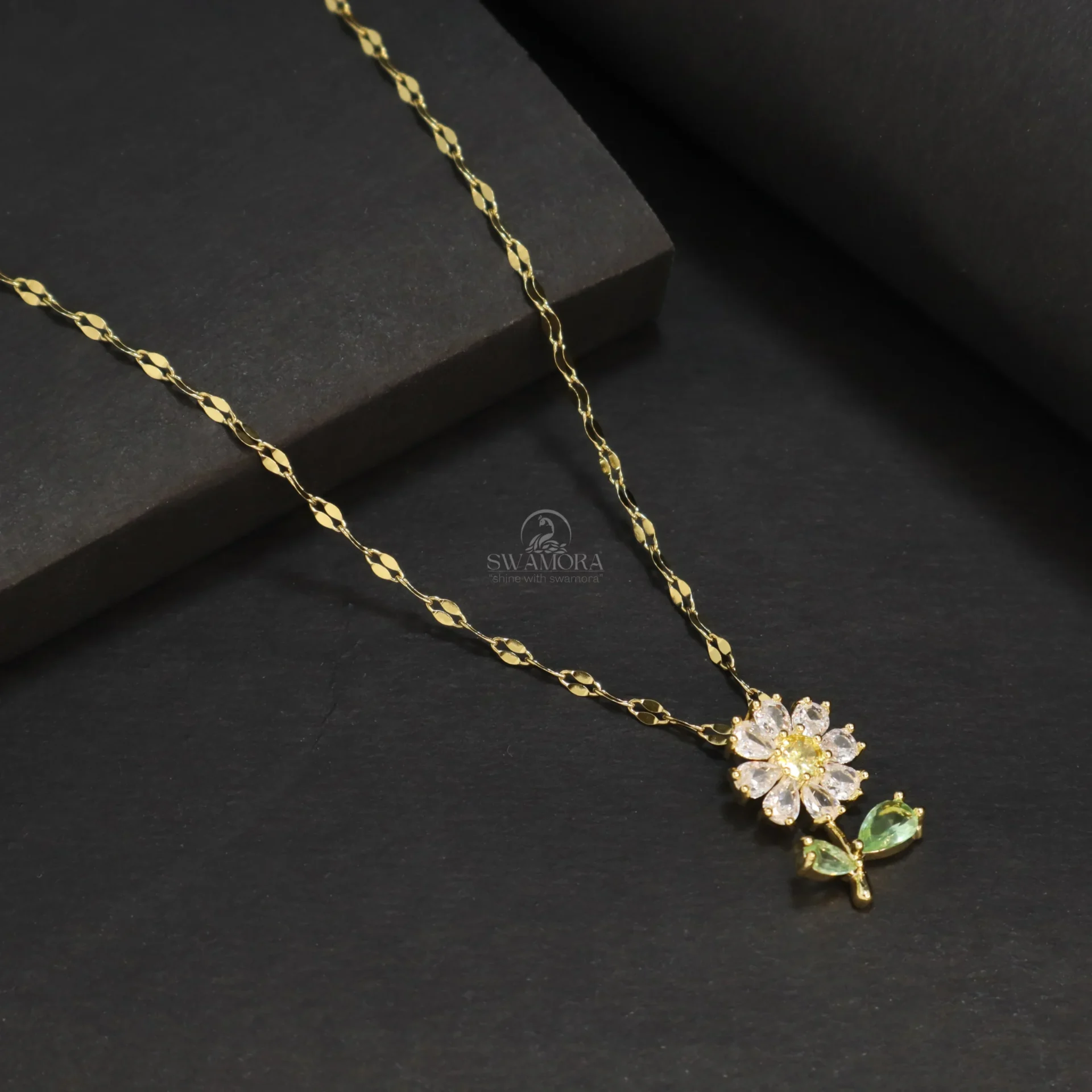 Introducing a beautiful and charming gold-plated sunflower pendant necklace for women! This necklace features a delicate sunflower pendant adorned with sparkling zircon crystals on its petals and center. The flower also has two small green leaves, enhancing its attractive appearance. This design gives the necklace a special and fresh look. The chain is made from high-quality material, providing a lovely golden shine and ensuring it lasts for a long time. Key Features: ⦁ Anti-tarnish: The high-quality gold plating prevents it from tarnishing quickly and helps maintain its golden shine. ⦁ Skin-friendly: This material is safe for your skin. ⦁ Long-lasting: The sturdy construction and good finish mean this chain can be worn for a long time. ⦁ The sunflower design with sparkling zircon crystals and leaf detail gives it a special and attractive look. ⦁ A great fashion accessory and style statement for women. ⦁ An excellent option for any special occasion or to add a beautiful and cheerful touch to everyday style. This beautiful sunflower pendant necklace will further enhance your beauty!